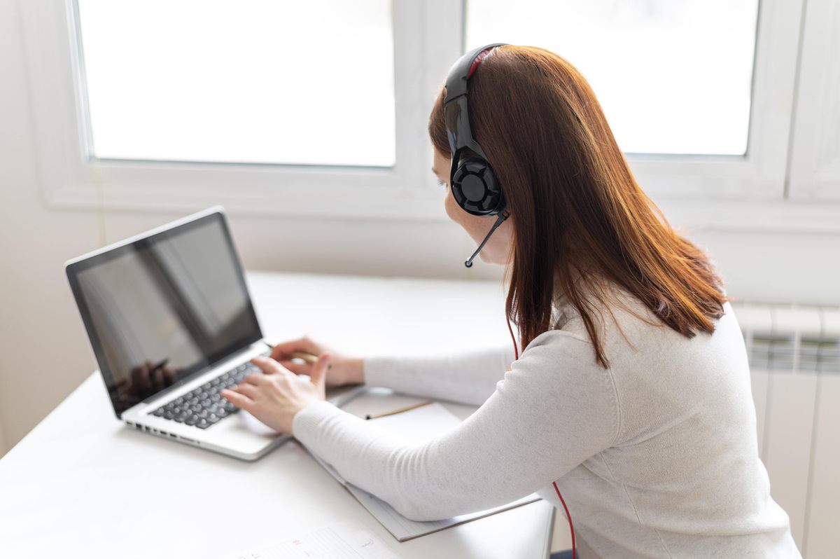 Programátorka píše do laptopu na bielom stole