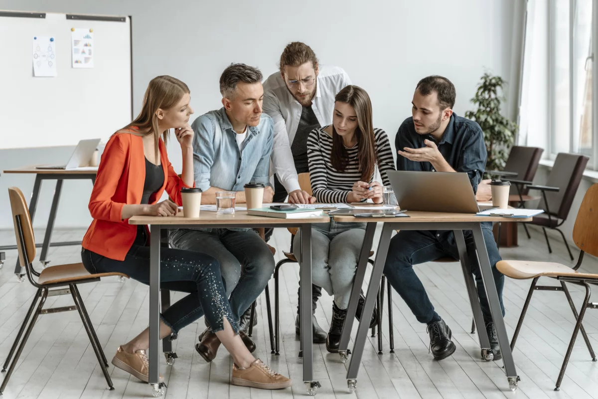 a project team of five young people sitting at a table looking at project materials